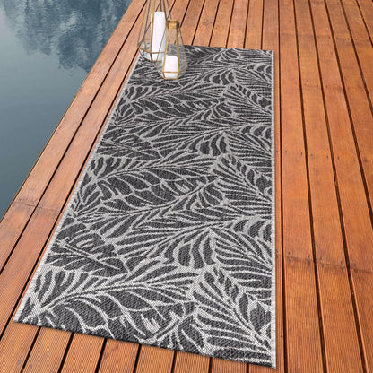 Botanical palm leaf outdoor rug styled with rattan dining furniture