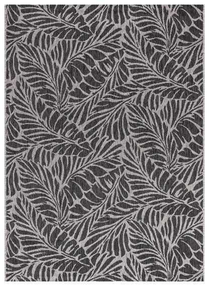 Black and gray tropical leaf outdoor rug on covered teak patio