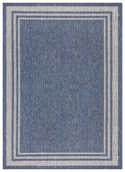 Navy and ivory bordered outdoor rug on covered teak patio