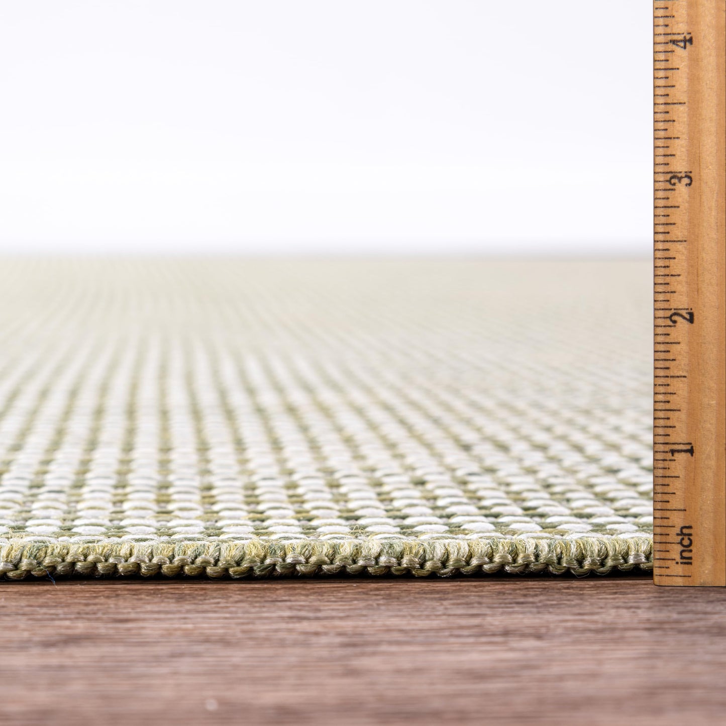 Bound edge detail of the solid green outdoor rug