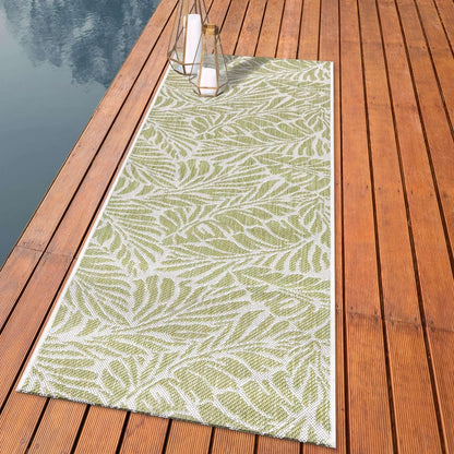 Botanical palm leaf outdoor rug styled with rattan dining furniture