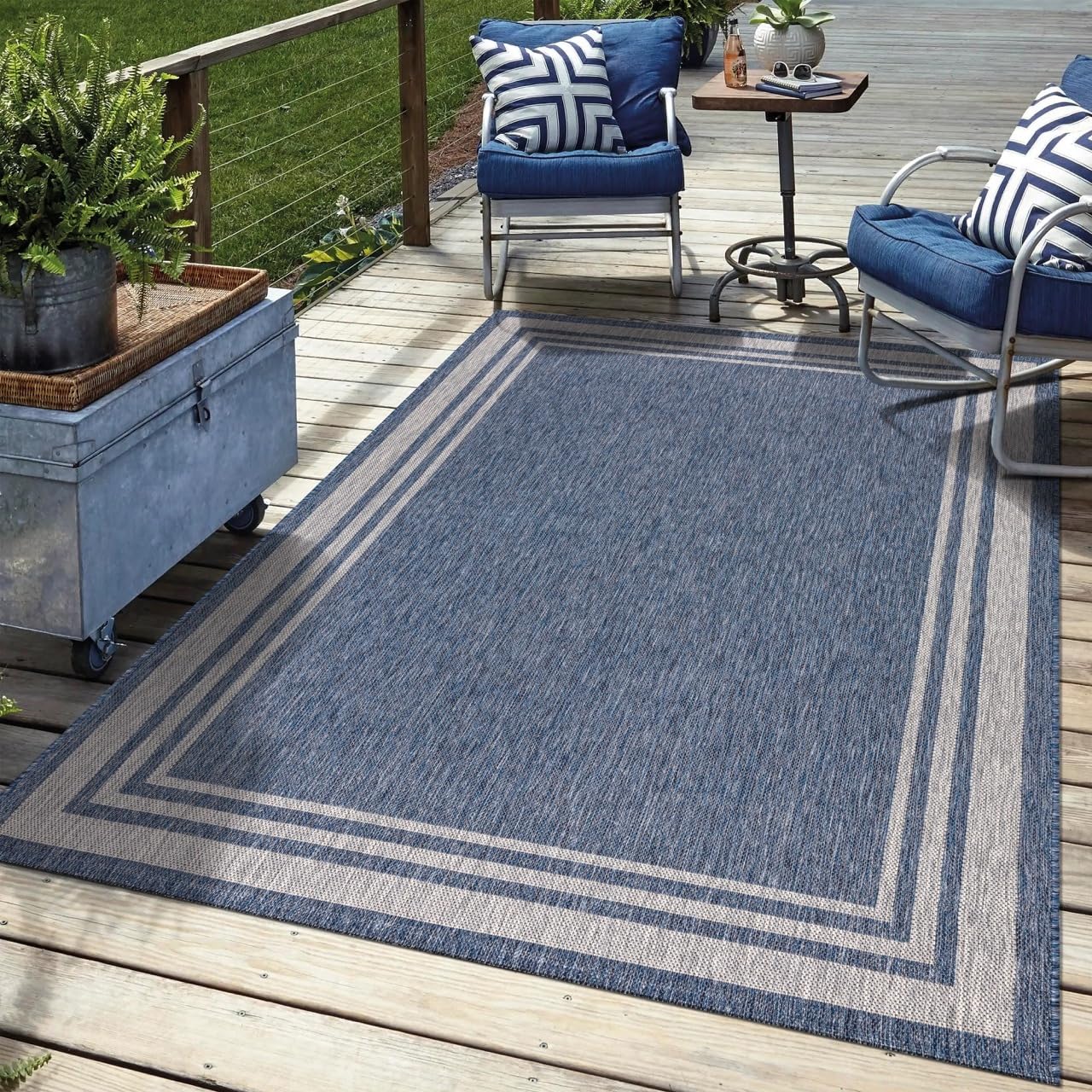 Navy bordered outdoor rug in garden seating area with greenery
