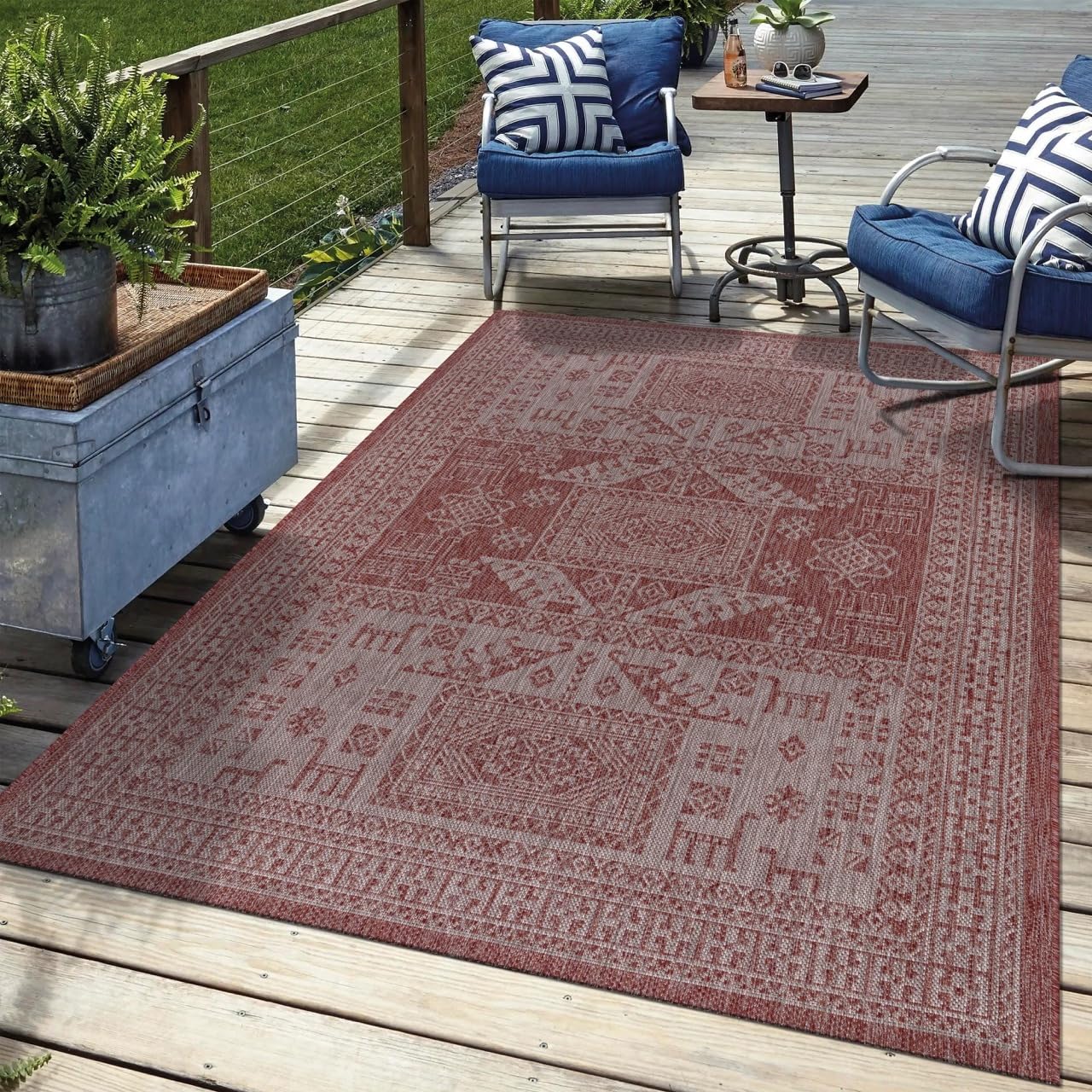Terracotta tribal outdoor rug in garden seating area with greenery
