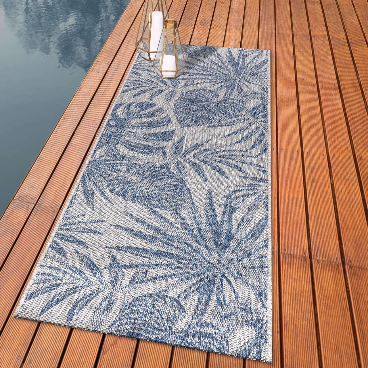 Lush monstera and palm outdoor rug styled with rattan dining furniture