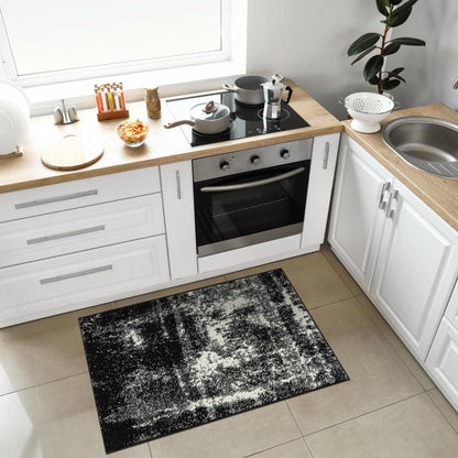 Low pile black abstract rug on light wood flooring