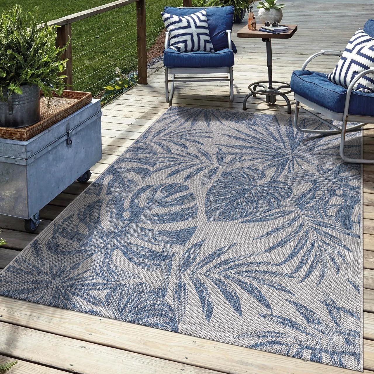 Navy tropical outdoor rug in garden seating area with palm greenery