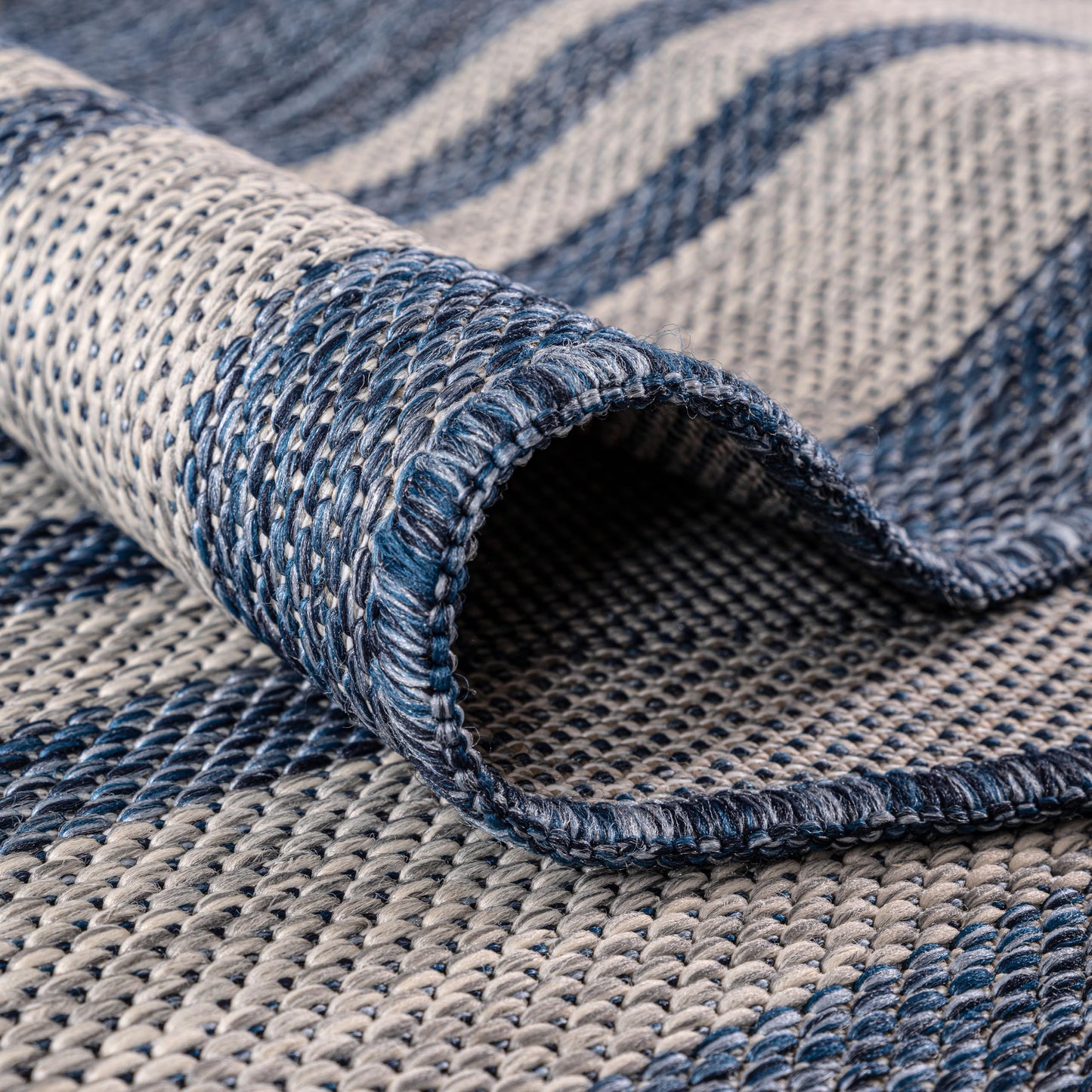Navy bordered rug in three-season sunroom with rattan furniture
