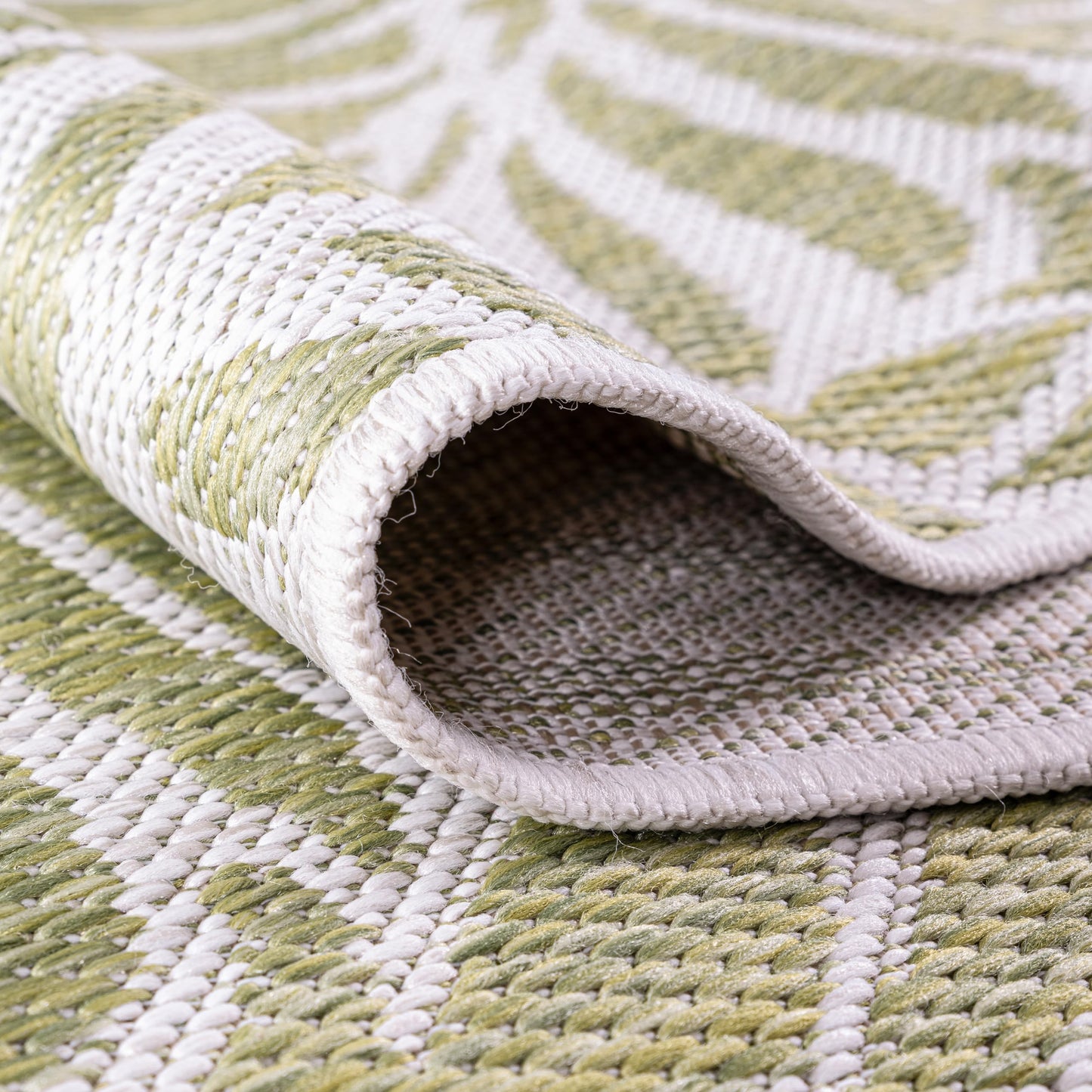 Green botanical rug in three-season sunroom with rattan furniture