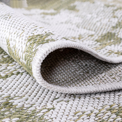 Green painterly rug in three-season sunroom with rattan furniture