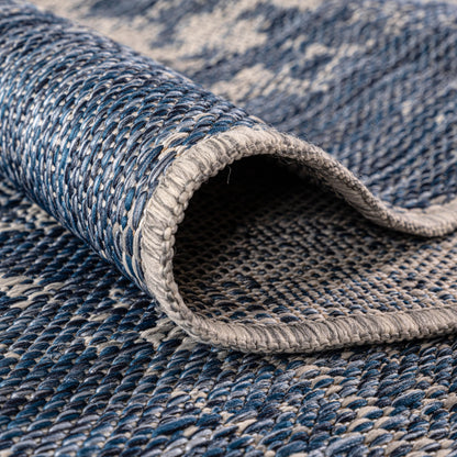 Navy painterly rug in three-season sunroom with rattan furniture