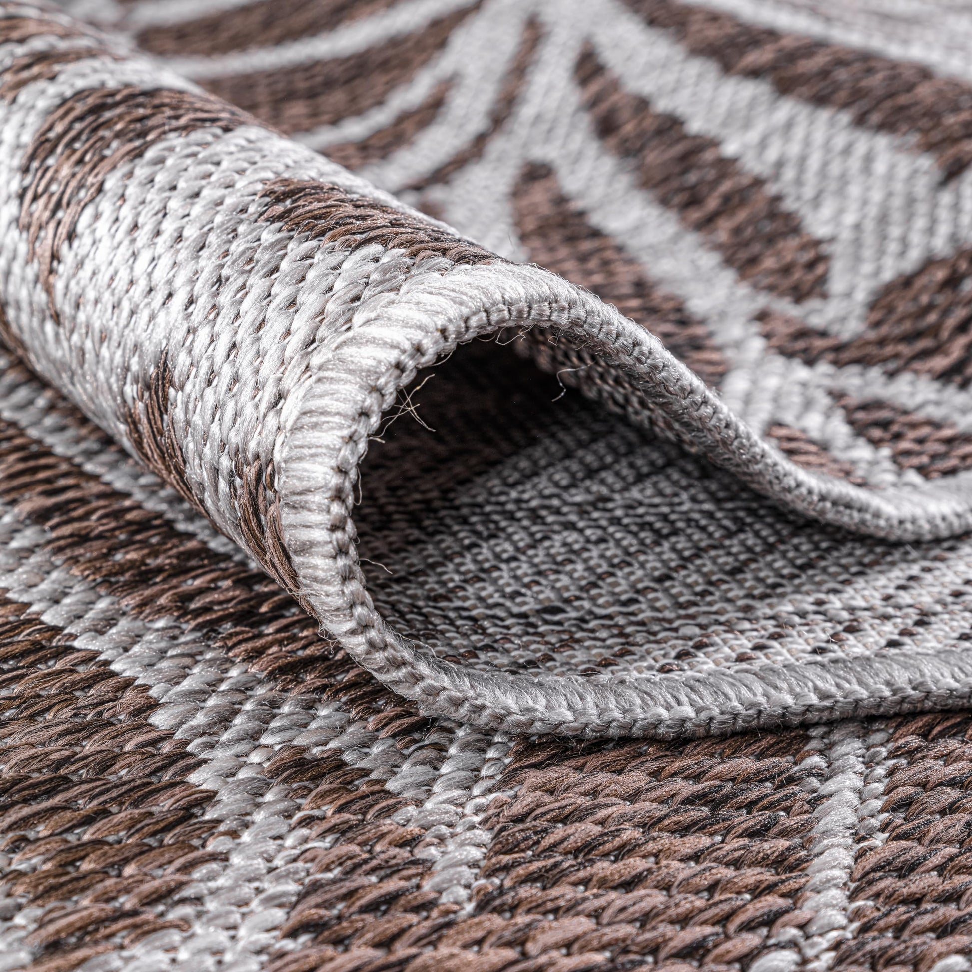Brown botanical rug in three-season sunroom with rattan furniture