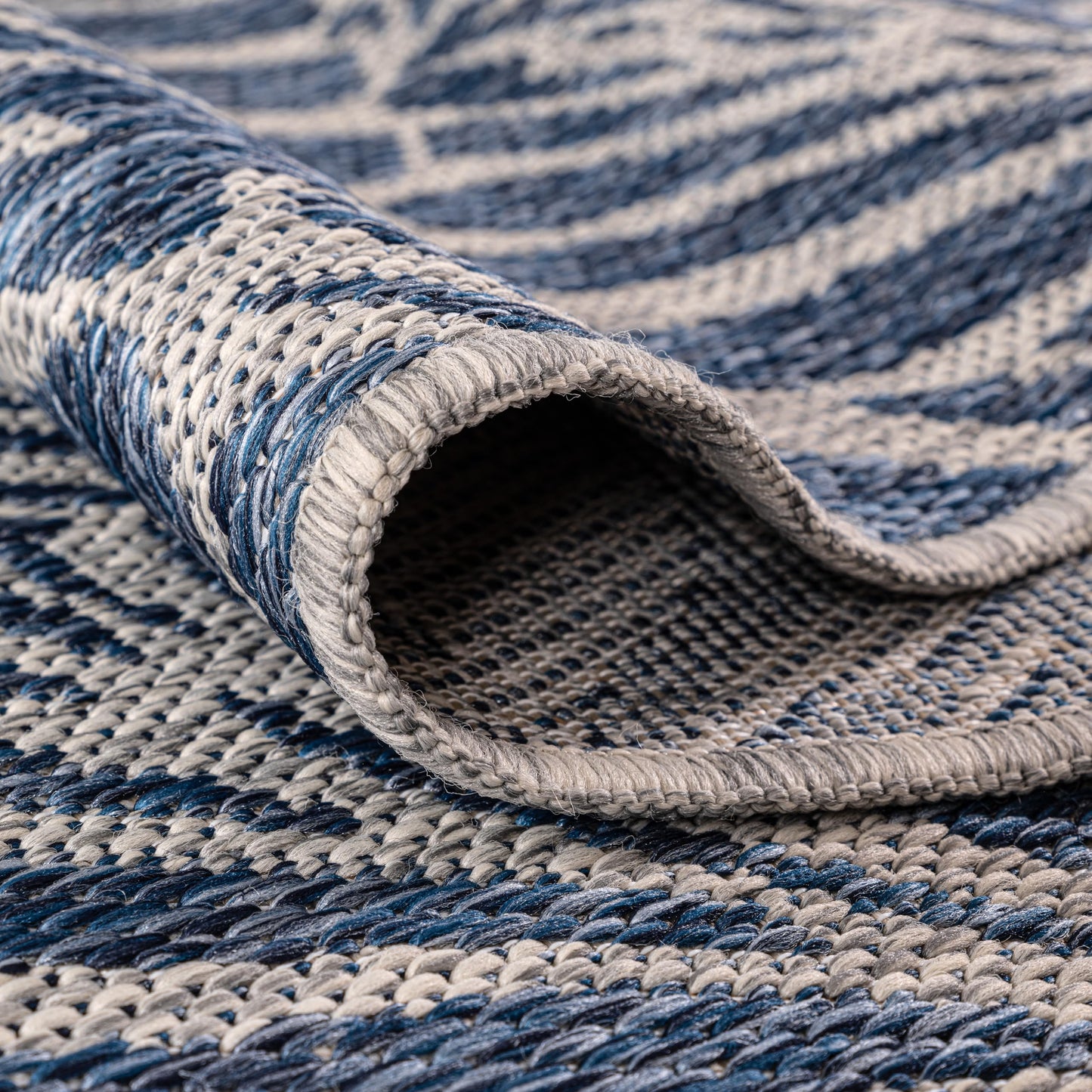 Navy botanical rug in three-season sunroom with rattan furniture