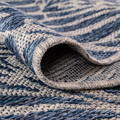 Navy botanical rug in three-season sunroom with rattan furniture