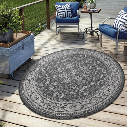 Black weatherproof Persian rug on stone patio with metal furniture